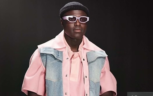 Fashion designer, runway and walking with black man in studio for showcase, clothes presentation and event. Wardrobe launch, luxury brand and collection with model on stage with dark background space